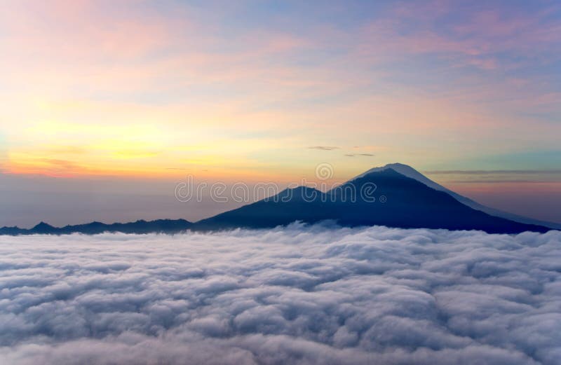 Nascer do sol acima das nuvens com vista para um vulcão montanhoso fotografia de stock royalty free