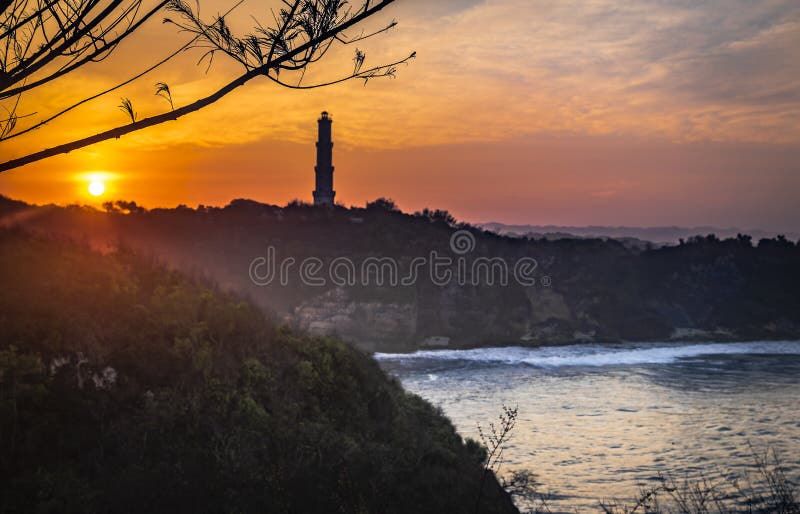 Nascer do sol bonito na praia do barão com fundo dourado do céu e do farol foto de stock Nascer do sol bonito na praia do barão com fundo dourado do céu e do farol foto de stock