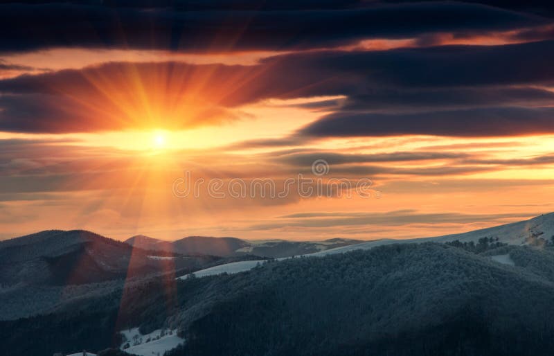 Beautiful sunrise in the winter mountains. Dramatic cloudy over sky. View of foggy hills and trees covered with rime. Beautiful sunrise in the winter mountains. Dramatic cloudy over sky. View of foggy hills and trees covered with rime.