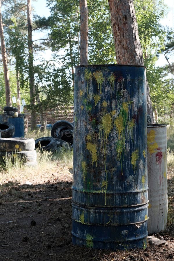 Nascondiglio di paintball Barilotto con le macchie dei colori differenti nella foresta il territorio per un gioco di squadra dell fotografia stock Nascondiglio di paintball Barilotto con le macchie dei colori differenti nella foresta il territorio per un gioco di squadra dell fotografia stock