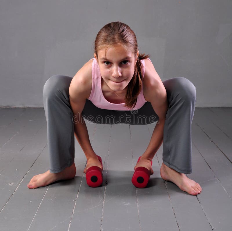 Nastolatek dziewczyna robi ćwiczeniom z dumbbells rozwijać z dumbbells mięśniami na popielatym tle Pełny długość portret nastolet obrazy stock Nastolatek dziewczyna robi ćwiczeniom z dumbbells rozwijać z dumbbells mięśniami na popielatym tle Pełny długość portret nastolet obrazy stock