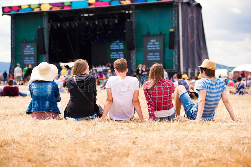 Nastolatkowie, lato festiwal muzyki, siedzi przed sceną obraz stock Nastolatkowie, lato festiwal muzyki, siedzi przed sceną obraz stock