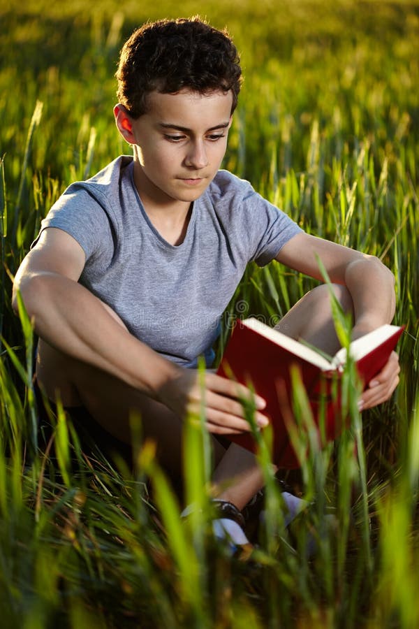 Nastoletni chłopak czyta książkę przy zmierzchem
