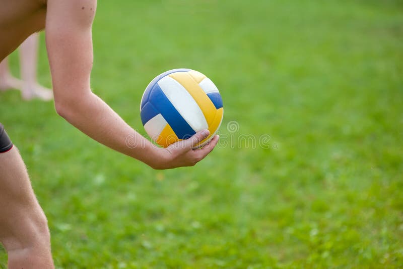 Nastoletnia chłopiec bawić się plażową siatkówkę Siatkówka gracz na trawie bawić się z piłką, siatkówki piłka w jego ręce zdjęcia stock Nastoletnia chłopiec bawić się plażową siatkówkę Siatkówka gracz na trawie bawić się z piłką, siatkówki piłka w jego ręce zdjęcia stock