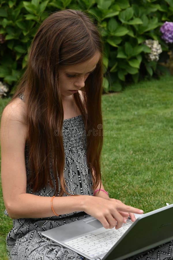 Teenage girl with laptop.Teenager with wonderful long brown hair sitting on the grass working with notebook. back to school. Teenage girl with laptop.Teenager with wonderful long brown hair sitting on the grass working with notebook. back to school