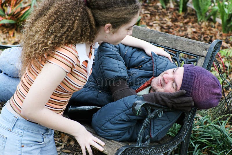 Teen girl volunteers to help homeless men in the park. Or daughter helping father. Teen girl volunteers to help homeless men in the park. Or daughter helping father.