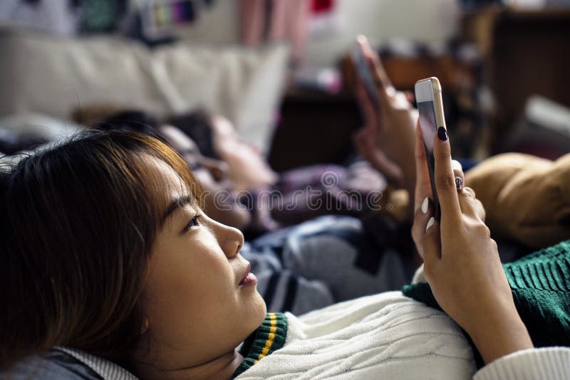 Nastoletnie dziewczyny używa smartphones na łóżkowym internecie w sen przyjęciu fotografia stock Nastoletnie dziewczyny używa smartphones na łóżkowym internecie w sen przyjęciu fotografia stock