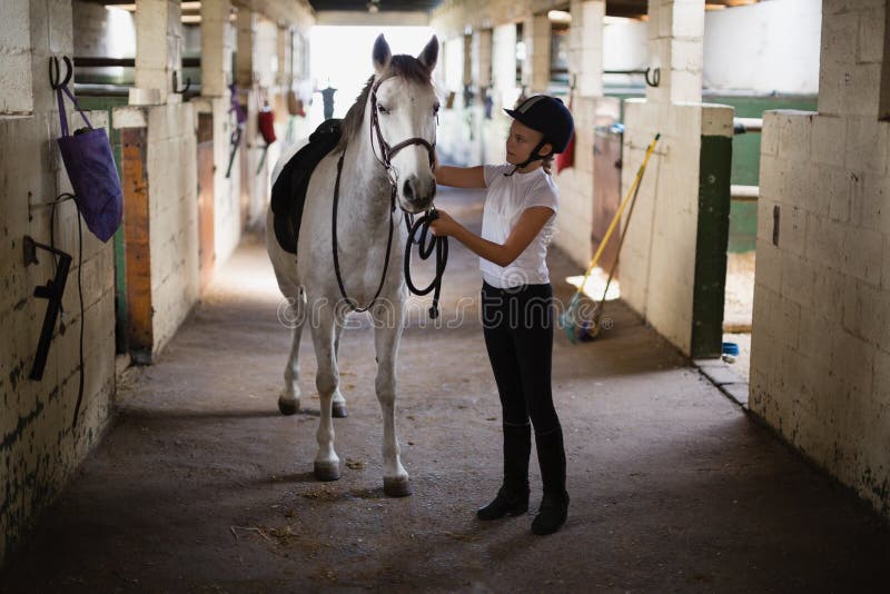 Teenage girl standing with horse in the stable. Teenage girl standing with horse in the stable