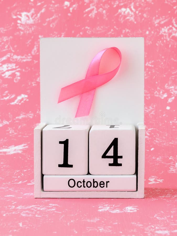 Pink ribbon of breast cancer awareness on a white wooden perpetual calendar with date 14 october. International breast cancer awareness month. Healthcare. Pink ribbon of breast cancer awareness on a white wooden perpetual calendar with date 14 october. International breast cancer awareness month. Healthcare