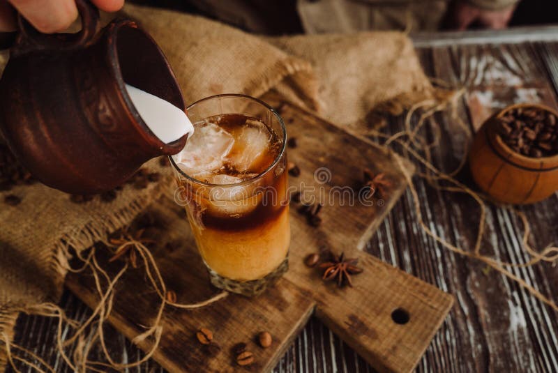 male barista pouring cream or milk into a glass of iced coffee 4. male barista pouring cream or milk into a glass of iced coffee 4