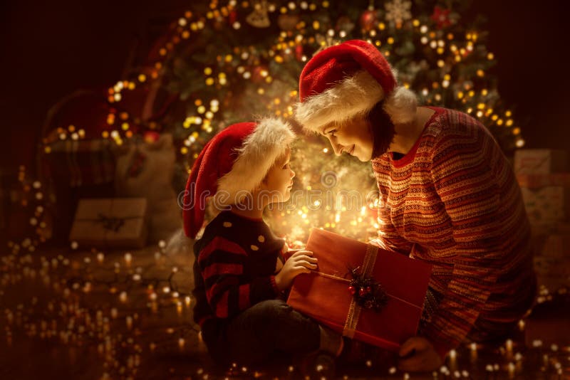 Natal aberto da família que ilumina a parte dianteira atual da caixa de presente da árvore do Xmas, mãe feliz com bebê fotos de stock