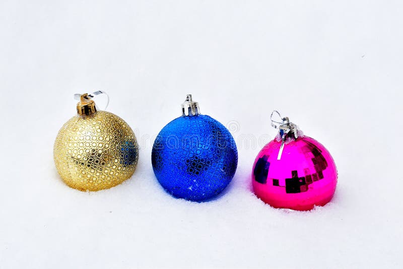 Christmas. Three brightly colored balls, a Christmas tree decoration lie on the white snow. Christmas. Three brightly colored balls, a Christmas tree decoration lie on the white snow.