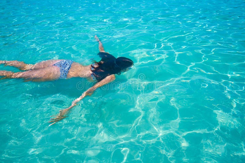 Bikini girl swimming in clear Ibiza beach tropical turquoise Mediterranean. Bikini girl swimming in clear Ibiza beach tropical turquoise Mediterranean