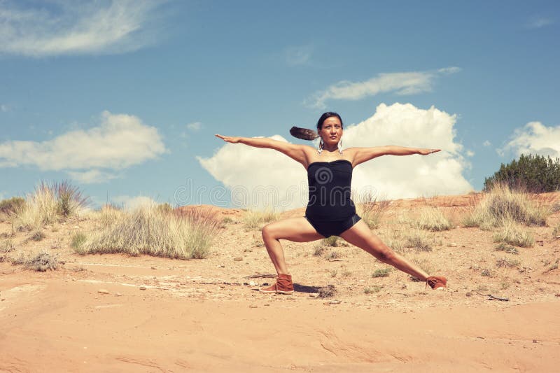 Native American Yoga Woman in her early 40`s posing in Warrior Pose photographed in New Mexico USA. She is wearing an eagle feather and hot yoga top and shorts with native american moccasins mixing the traditional and the contemporary. Native American Yoga Woman in her early 40`s posing in Warrior Pose photographed in New Mexico USA. She is wearing an eagle feather and hot yoga top and shorts with native american moccasins mixing the traditional and the contemporary.