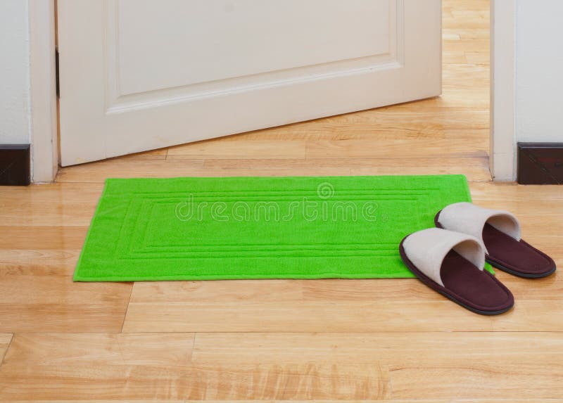 Green doormat and house slippers in front of the door. Green doormat and house slippers in front of the door