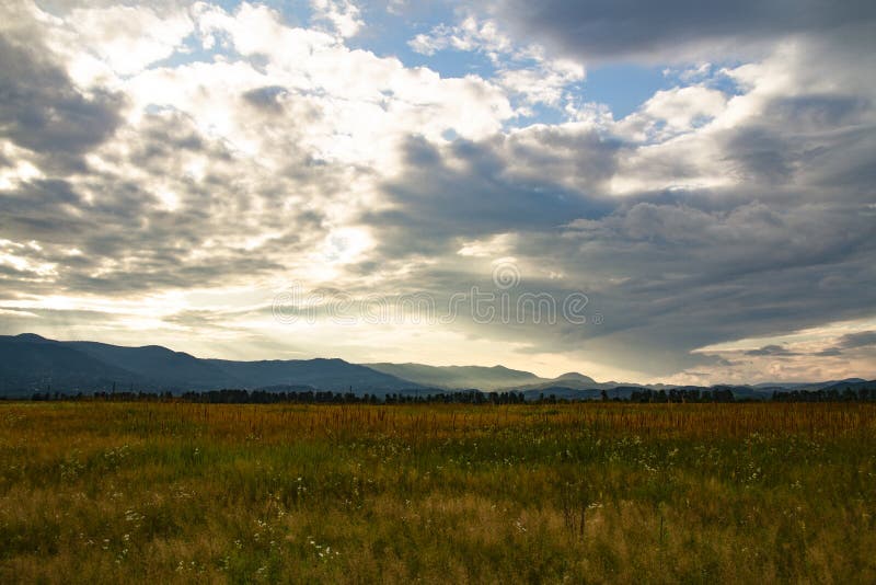 Natural Background Field of Grass, Mountains and Sky Stock Image