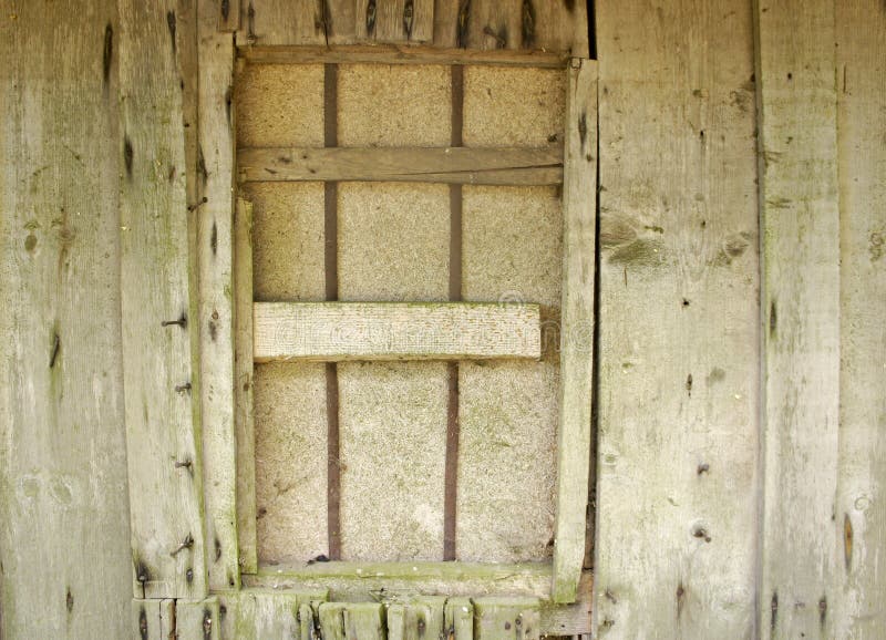 Natural color aged untreated untreated wood storage wall with protruding iron nails and boarded up window. Natural color grunge vintage background rustic aged royalty free stock image Natural color aged untreated untreated wood storage wall with protruding iron nails and boarded up window. Natural color grunge vintage background rustic aged royalty free stock image
