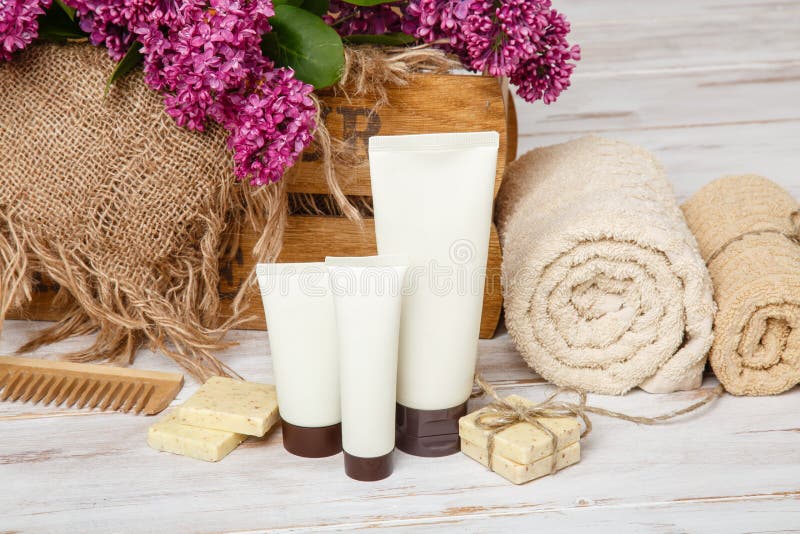 Natural cosmetics with lilac flowers. Set of cream and towel rolls.