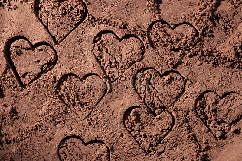 Natural dark brown cocoa powder with a picture of a hearts, textured background, closeup, top view royalty free stock photo