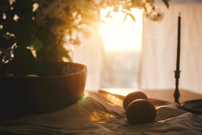 Natural Easter eggs and vintage candle in sunset warm light on linen fabric on rustic table with cherry flowers and green leaves. Happy Easter. Rural still stock photography Natural Easter eggs and vintage candle in sunset warm light on linen fabric on rustic table with cherry flowers and green leaves. Happy Easter. Rural still stock photography