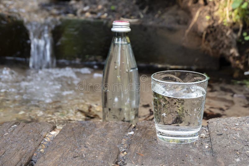 Natural Ecological Spring Water. Glass Bottle and Glass of Cold Water
