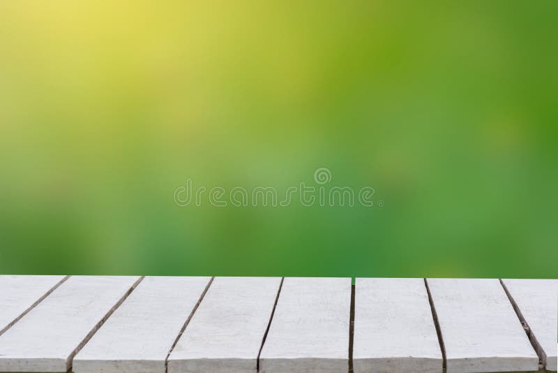 Natural green background with selective focus. The green background has a bokeh leaf and grass on a white wooden floor. Empty tabl