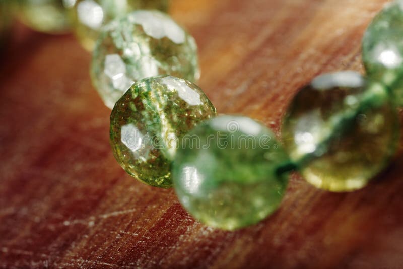 Natural green jade nephrite stones beads on wooden surface. Green grassy color round stone beads macro image