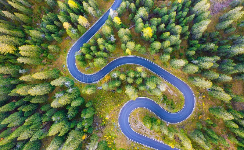 Natural landscape from air. Aerial view on the road and forest at the autumn time. An aerial summer landscape in the Dolomite Alps