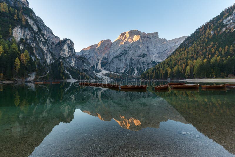 Natural landscapes of the lake Braies Lago di Braies with morning fog and reflection of the mountain peak in Dolomites, Italy