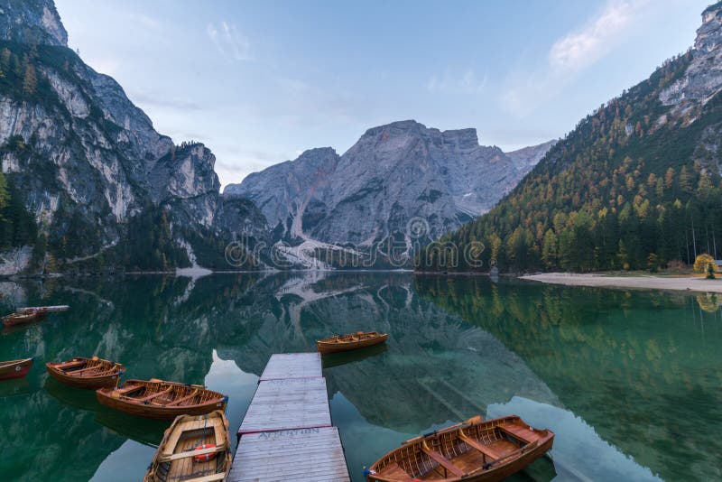 Natural landscapes of the lake Braies Lago di Braies with morning fog and reflection of the mountain peak in Dolomites, Italy