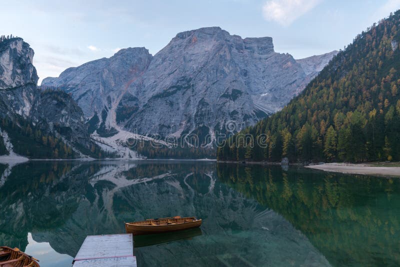 Natural landscapes of the lake Braies Lago di Braies with morning fog and reflection of the mountain peak in Dolomites, Italy