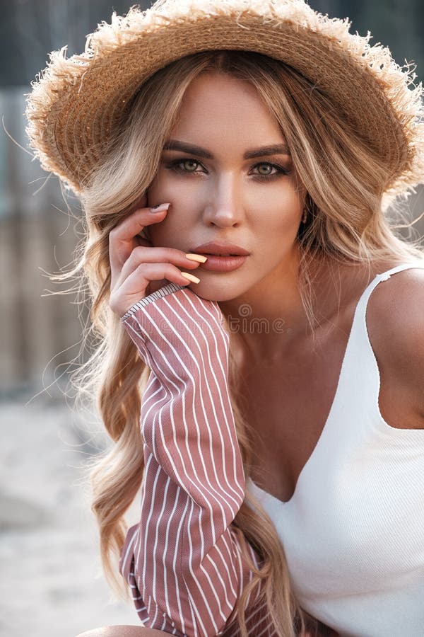 Natural lifestyle portrait of a beautiful gorgeous young woman with long loose blonde hair in a straw hat. Countryside landscape a royalty free stock photo Natural lifestyle portrait of a beautiful gorgeous young woman with long loose blonde hair in a straw hat. Countryside landscape a royalty free stock photo