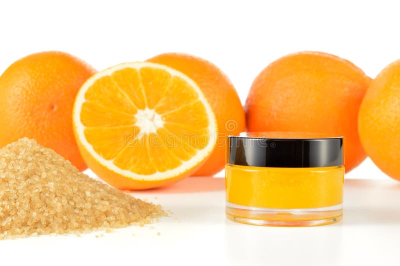 Natural orange sugar lip scrub on white background. Orange cosmetic in a glass jar with oranges and sugar in a background. Natural orange sugar lip scrub on white background. Orange cosmetic in a glass jar with oranges and sugar in a background.