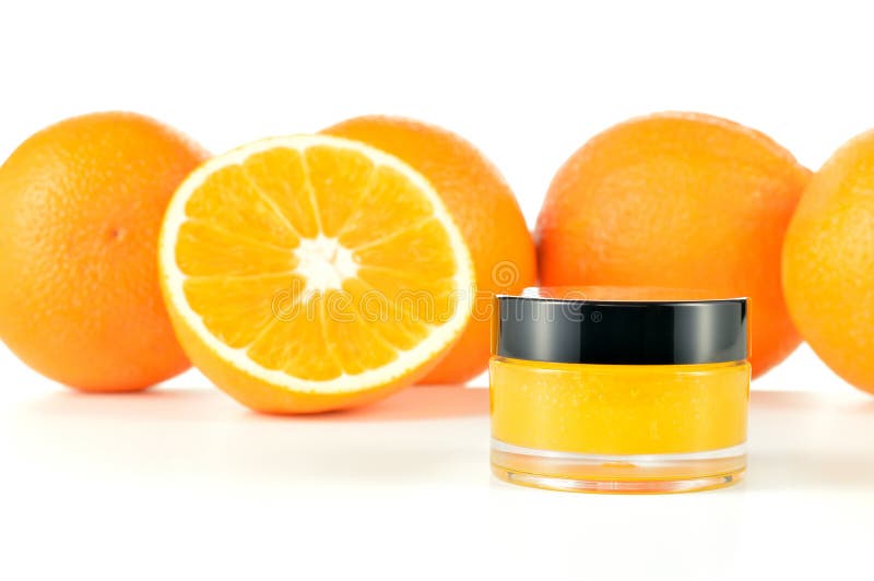 Natural orange sugar lip scrub on white background. Orange cosmetic in a glass jar with oranges in a background. Natural orange sugar lip scrub on white background. Orange cosmetic in a glass jar with oranges in a background.