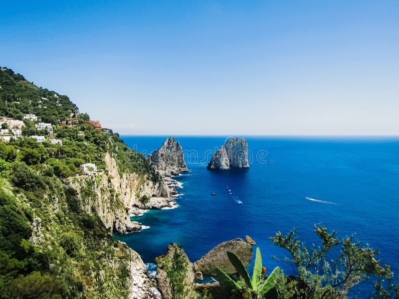 Natural rock arches and cliffs on the coast Sorrento and Capri, Italian islands with crystal clear waters where tourist boats