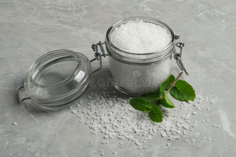 Natural Sea Salt in Glass Jar and Mint on Light Grey Marble Table Stock