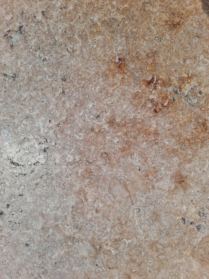 Natural stone surface with rough texture, featuring earthy brown, beige, and gray tones with subtle fossil-like patterns.