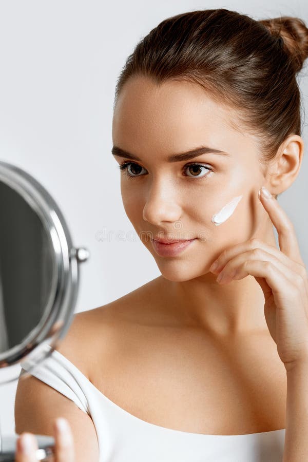 Naturalnie piękna brunetki kobieta z doskonałą skórą stosuje opieki śmietankę jej twarz stosowanie opieki skóry przejrzystego lak obrazy stock Naturalnie piękna brunetki kobieta z doskonałą skórą stosuje opieki śmietankę jej twarz stosowanie opieki skóry przejrzystego lak obrazy stock