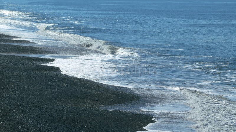 Nature Concept. Beach With Pebble Stones. Blue Ocean Or Sea Wave Washes The Shore. Slow motion.