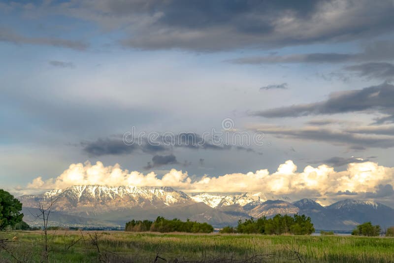 Natureza cênico com a montanha nevado ensolarado e o céu nebuloso sobre o lago e o vale imagens de stock royalty free Natureza cênico com a montanha nevado ensolarado e o céu nebuloso sobre o lago e o vale imagens de stock royalty free