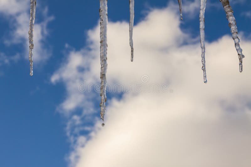 Naturliga istappar med vattendroppar mot den blåa himlen med moln arkivfoto Naturliga istappar med vattendroppar mot den blåa himlen med moln arkivfoto