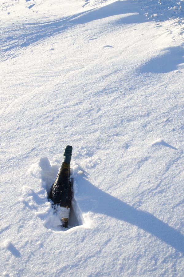 Vertical view of bottle of sparkling wine chilling in snow bank. Vertical view of bottle of sparkling wine chilling in snow bank