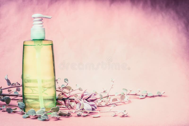 Natuurlijke cosmetische productfles met groene lotion of tonische vloeistof met verse kruiden en bloemen bij roze achtergrond Gez stock foto Natuurlijke cosmetische productfles met groene lotion of tonische vloeistof met verse kruiden en bloemen bij roze achtergrond Gez stock foto