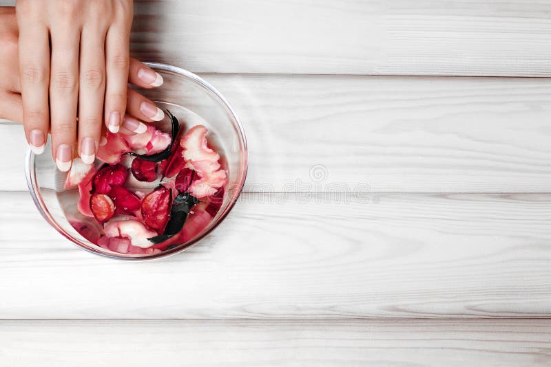 Natuurlijke Manicure, Handzorg Doorwekende Vingerspijkers in Bad met Kruidenolie en Bloemen op Witte Houten Lijst De ruimte van h royalty-vrije stock fotografie Natuurlijke Manicure, Handzorg Doorwekende Vingerspijkers in Bad met Kruidenolie en Bloemen op Witte Houten Lijst De ruimte van h royalty-vrije stock fotografie