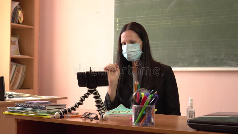 Nauczyciel w masce ochronnej. samouczek wideo podczas kwarantanny. młody nauczyciel prowadzi lekcję filmując się na