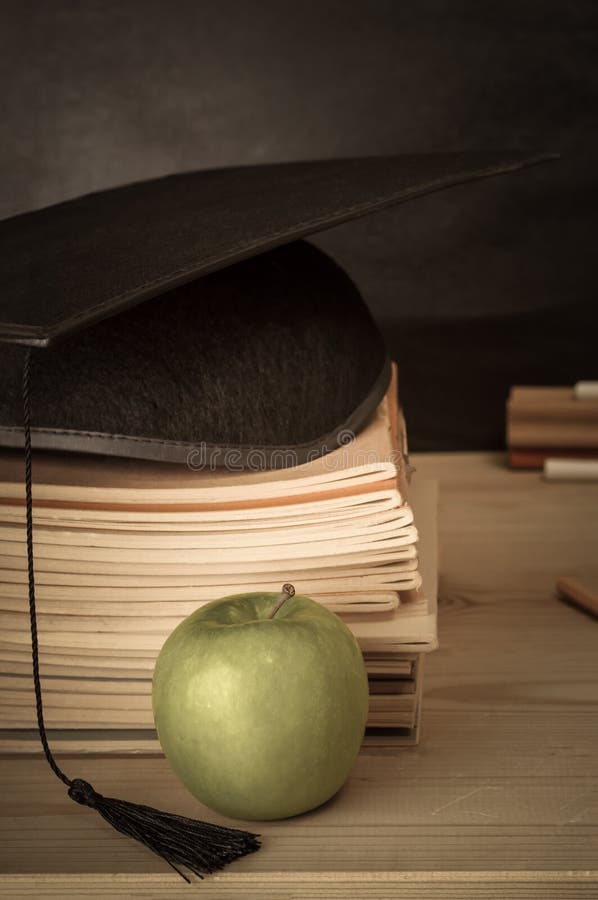 Nauczyciela biurko z książkami Brogować, Mortarboard, Apple i Chalkb, fotografia stock Nauczyciela biurko z książkami Brogować, Mortarboard, Apple i Chalkb, fotografia stock