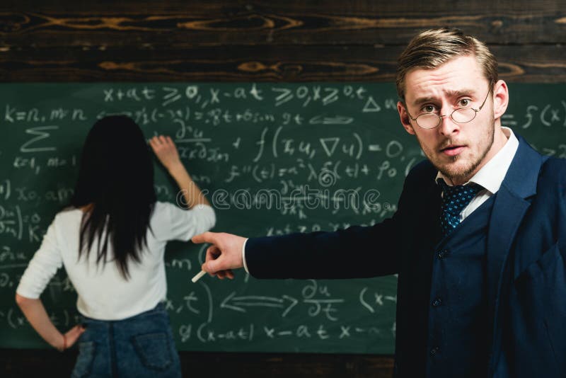Nauczyciela punktu palec przy uczniem robi sumom Nauczyciel z szkłami na mądrze twarzy obrazy stock Nauczyciela punktu palec przy uczniem robi sumom Nauczyciel z szkłami na mądrze twarzy obrazy stock