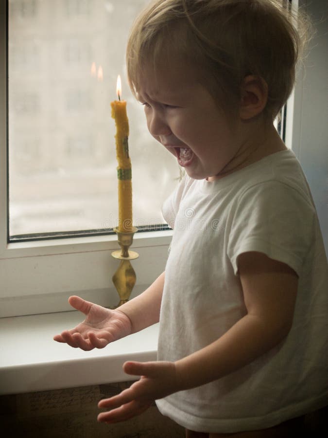 The naughty little boy touched the candle fire royalty free stock image The naughty little boy touched the candle fire royalty free stock image