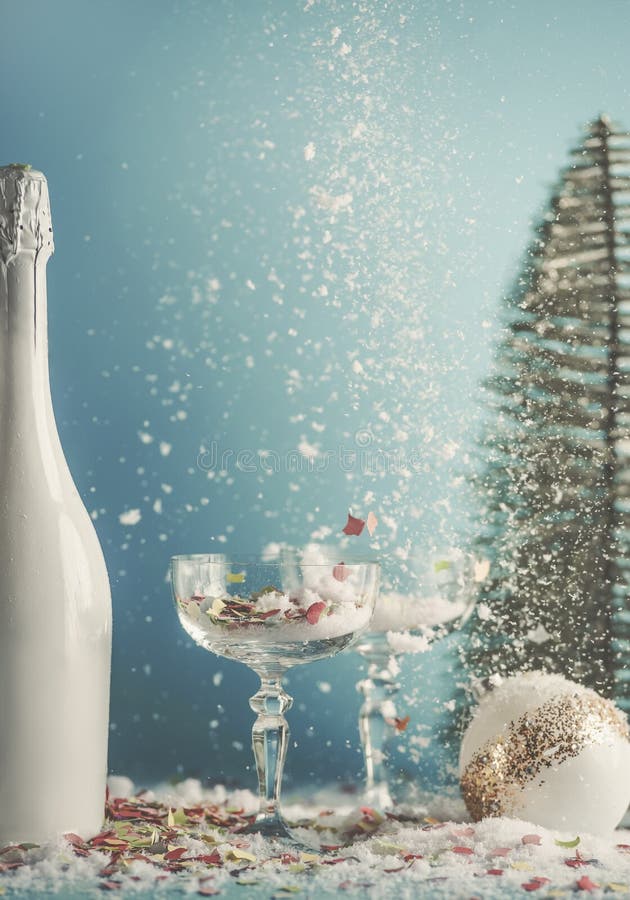 Navidad y años nuevos antecedentes con copas de champán y botella de champán blanco. bauble de navidad y árbol de navidad en. navidad bauble y árbol de navidad en fondo azul con nieve y confetti. vista frontal.