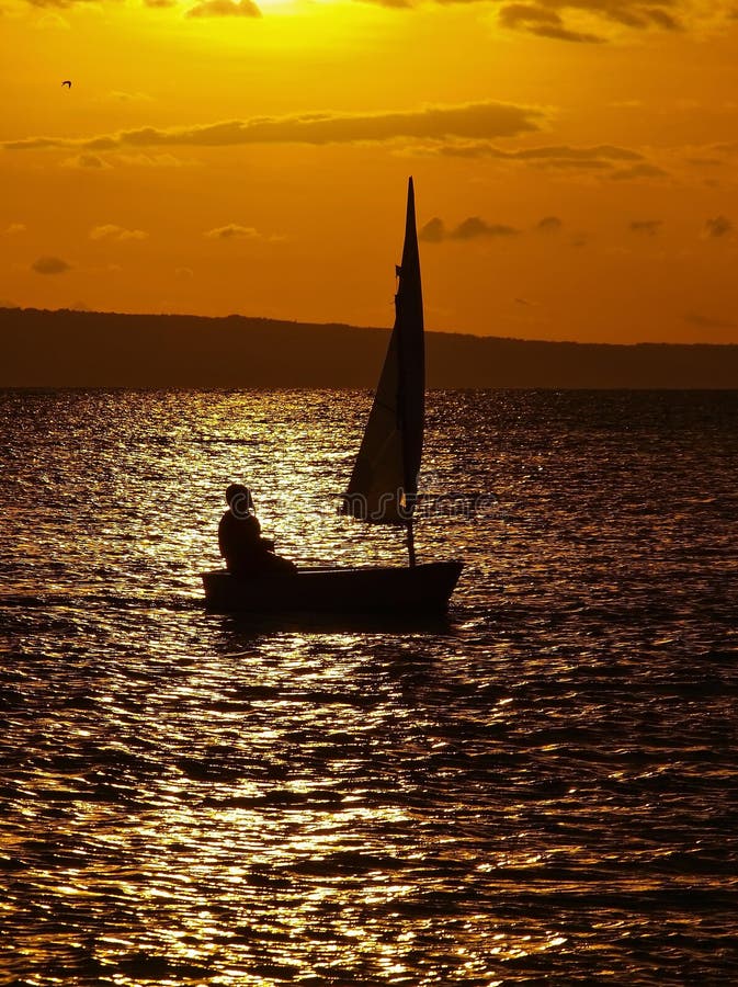 Little alone girl in a small wooden boat (with a open sails) sailing in the golden sunset at Adriatic sea (Croatia - Dalmatia). Vertical color photo. Little alone girl in a small wooden boat (with a open sails) sailing in the golden sunset at Adriatic sea (Croatia - Dalmatia). Vertical color photo.